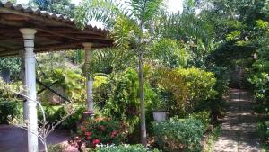 a garden with a wooden pergola and a palm tree at Village Garden Inn in Parasangahawewa