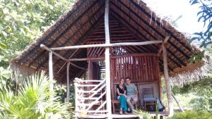 Parasangahawewa的住宿－村莊花園住宿加早餐旅館，两个人坐在一个小小屋的门廊上