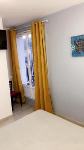 a bedroom with yellow curtains and a window at Hotel Les Arcades in Rouen