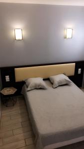 a bedroom with a bed with two pillows and two lights at Hotel Les Arcades in Rouen