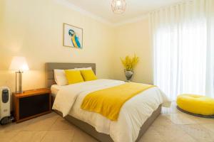 a bedroom with a bed with yellow pillows and a window at Heart of Ocean Dulpex Estoril in Estoril