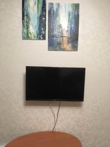 einen Flachbild-TV an der Wand mit zwei Gemälden in der Unterkunft Затишна двокімнатна квартира in Vatutine