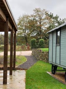 a house with a stone wall next to a yard at Glamping at Holly Grove Farm in Stoke on Trent