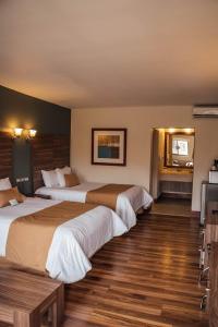 two beds in a hotel room with wooden floors at Best Western Cumbres Inn Cd. Cuauhtemoc in Cuauhtémoc