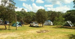 a group of tents and a car parked in a field at Camping do Delei in São Thomé das Letras