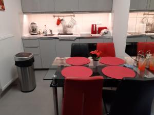 a kitchen with a black table and red chairs at Szalók Spa Apartman Egerszalók in Egerszalók