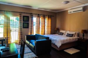 a bedroom with a bed and a blue couch at The Exclusive Guesthouse in Kempton Park +53 photos