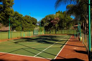 a tennis court with trees and a fence at The Exclusive Guesthouse in Kempton Park