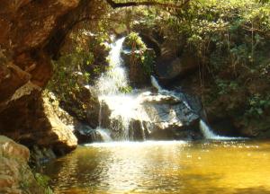 a waterfall in the middle of a pool of water at Camping do Delei in São Thomé das Letras
