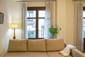 ein Sofa im Wohnzimmer mit Fenster in der Unterkunft Ispal Apartment & Parking Seville Historic Center vutse06601 in Sevilla