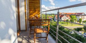 un balcón con una silla de madera y una mesa. en Apartament przy Porcie w Krynicy Morskiej en Krynica Morska