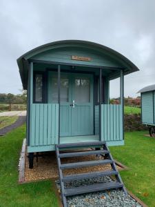 a small green building with a staircase in the grass at Glamping at Holly Grove Farm in Stoke on Trent