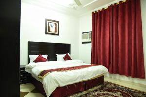 a bedroom with a large bed with red curtains at شقق جنان المفروشة Jenaan Apartments in Najran