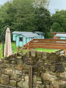 pared de piedra con sombrilla y edificio en Glamping at Holly Grove Farm en Stoke on Trent