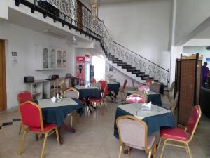 a restaurant with tables and chairs and a staircase at Sophia Hotel in Dar es Salaam