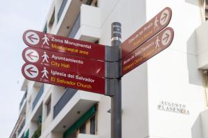 ein Straßenschild mit vielen Schildern an einer Stange in der Unterkunft Ispal Apartment & Parking Seville Historic Center vutse06601 in Sevilla