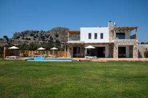a stone house with a pool and a mountain at Villa Alkyoni Lindos in Lindos