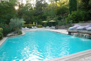 einen Pool im Garten mit Stühlen und Sonnenschirmen in der Unterkunft Châteauzen in Madières