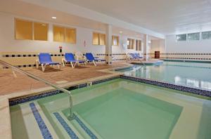 a swimming pool with blue chairs in a building at Candlewood Suites-West Springfield by IHG in West Springfield