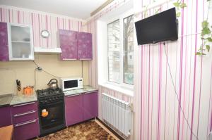 クルスクにあるАпартаменты на Советской 12のキッチン(紫色のキャビネット付)、壁掛けテレビが備わります。