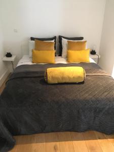 a large bed with a black blanket and yellow pillows at Château Martin in Esneux