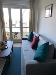 a living room with a couch and a table with pillows at Joie Paris Parc Expo - Issy Les Moulineaux in Issy-les-Moulineaux