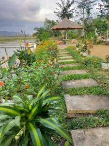 a garden with stepping stones and flowers and a umbrella at Phong Nha Rice Field Homestay in Phong Nha