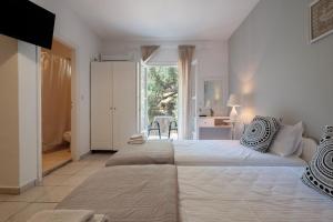 a white bedroom with two beds and a desk at Stavroula Studios in Paleokastritsa