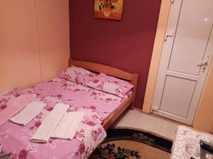 a small bedroom with a pink bed with towels on it at Guest house Mirijevski Konak in Belgrade