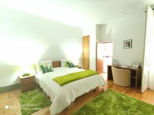 a bedroom with a large bed with a green blanket at Alojamento Local F&B in Guimarães
