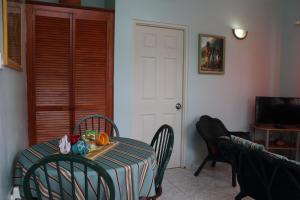 a dining room with a table and chairs and a television at The AnSwin Apartment in Roseau