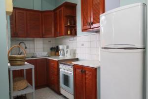 cocina con armarios de madera y nevera blanca en The AnSwin Apartment, en Roseau