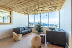 a living room with couches and chairs and a large window at Les ARCS 1600 - SKI AUX PIEDS - MAGNIFIQUE DUPLEX 12 PERSONNES in Bourg-Saint-Maurice