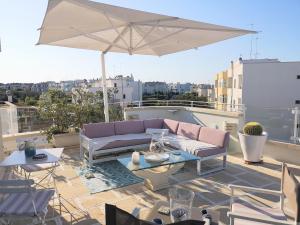a patio with a couch and an umbrella on a roof at Le Terrazze in Otranto