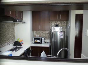 a kitchen with a stainless steel refrigerator and wooden cabinets at Fantastic Affordable high end condominium heart of the Cebu city in Cebu City
