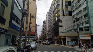 a busy city street with cars and people and buildings at Quitinete Centro de Guarapari. in Guarapari