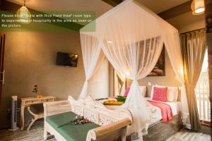 a bedroom with a canopy bed with white curtains at Ayu Duwur Beji in Ubud