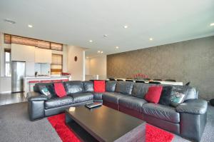 a living room with a leather couch and a table at Lakeview 5BR Apartment Walk to Town in Queenstown +18 photos