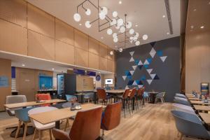a restaurant with tables and chairs in a cafeteria at Holiday Inn Express Ningbo City Center by IHG in Ningbo