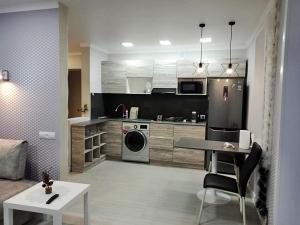 a kitchen and living room with a table and a stove at 2х комнатные апартаменты VIP на Назарбаева 44 in Pavlodar