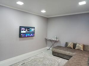 een woonkamer met een bank en een flatscreen-tv bij 2х комнатные апартаменты VIP на Назарбаева 44 in Pavlodar