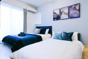 dwa łóżka w pokoju z białym i niebieskim w obiekcie Sou w mieście Fujisawa