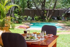 a table with a plate of food next to a pool at Nguni Lodge in Victoria Falls