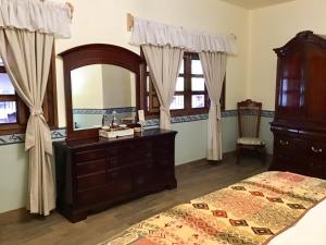 een slaapkamer met een bed, een dressoir en een spiegel bij Casa Tía Anita, Hotel Boutique in Mascota