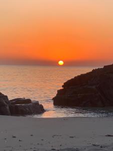 a sunset over a beach with rocks and the ocean at I Quattroventi in Muravera