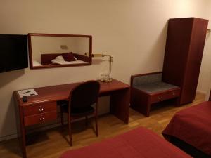 Zimmer mit einem Schreibtisch, einem Spiegel und einem Bett in der Unterkunft Hotell Åsen in Anderstorp