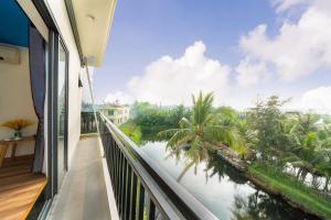a balcony with a view of the water and palm trees at Ri's House Hoi An Homestay in Hoi An