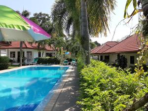 a swimming pool in front of a house with a umbrella at Smile House & Pool in Rawai Beach