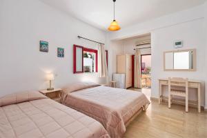 a bedroom with two beds and a table and a desk at Pension The Flower in Oia