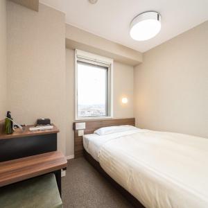 een hotelkamer met een bed en een raam bij Super Hotel Joetsu Myoko-Eki Nishiguchi in Joetsu